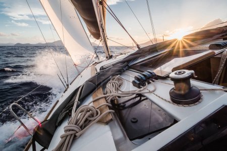 Jacht segelt schnell auf See mit Wellen im Sonnenuntergang in Richtung Äolische Inseln in Italien