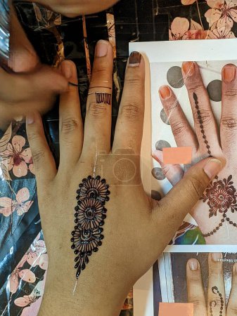 Téléchargez les photos : Une main ornée de motifs au henné complexes, tourbillonnant de brun rougeâtre, créant une œuvre d'art captivante et temporaire. Points focaux sélectifs - en image libre de droit