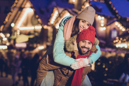 Foto von schönen Liebhabern junges Paar huckepack Umarmung tragen Mütze Jacke Schal Handschuhe gehen am Wochenende.