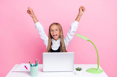 Photo of young beautiful schoolkid girl blonde hair eyeglasses excited fists up celebrate her homework laptop online isolated on pink color background.
