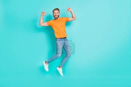Foto in voller Größe von optimistischen zufriedenen Mann muskulösen Bart tragen orangefarbene T-Shirt Jeans fliegen direkt auf sich selbst isoliert auf teal Farbhintergrund.