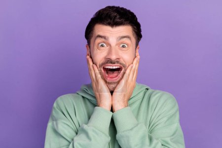 Closeup photo of funny astonished positive student guy touch cheeks palms open mouth unexpected good news shopping day isolated on violet color background.