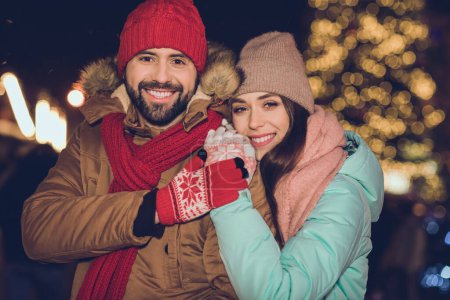 Foto von süßen jungen Liebhabern Umarmung tragen Mütze Jacke Schal Handschuhe in der Nähe von Baum an Neujahr.