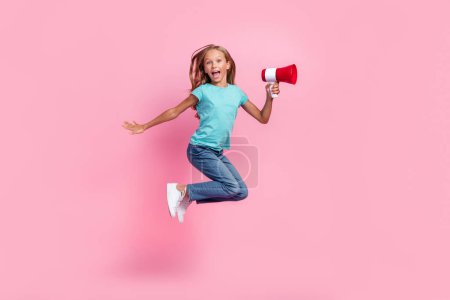 Full length photo of cute impressed small kid wear turquoise t-shirt jumping high rising toa isolated pink color background.