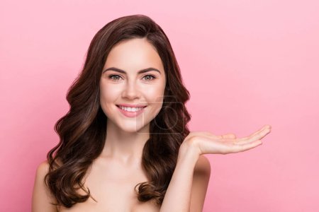 Photo of young adorable woman promoter hold hands lifting moisturizing cream isolated over pink color background.
