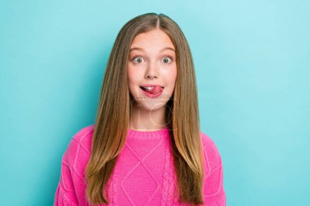 Foto von positiven fröhlich beeindruckt Mädchen gerade Frisur tragen rosa Strickpullover Zunge lecken Zähne isoliert auf blauem Hintergrund.