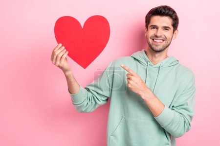 Photo of positive cheerful man bristle beard hold big symbol love red paper heart finger pointing his feelings girlfriend isolated on pink color background. Poster 621734694