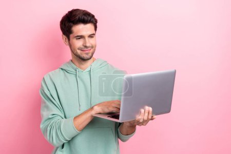 Photo of successful positive entrepreneur businessman hold his new macbook pro typing his accountant stats this period isolated on bright pink color background.
