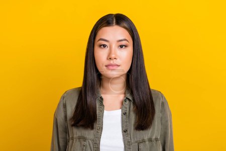 Photo of good mood serious gorgeous woman with straight hairdo dressed gray shirt look at camera isolated on yellow color background.