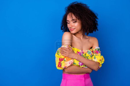 Photo of adorable cute girl dressed off shoulders blouse embracing herself empty space isolated blue color background.