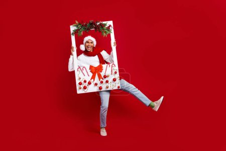Full-Size-Porträt des aufgeregten Kerl Hände halten Papier Weihnachtszeit dekoriert Albumkarte isoliert auf rotem Hintergrund.
