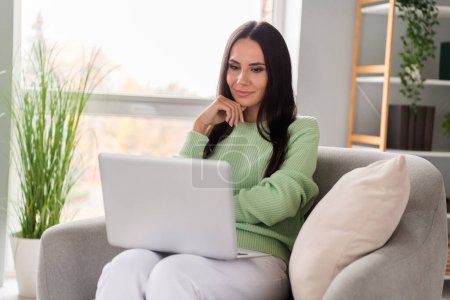 Photo of concentrated focused serious successful lady boss sit cozy chair home workspace watching listen video report reading cv resume . Poster 626242486