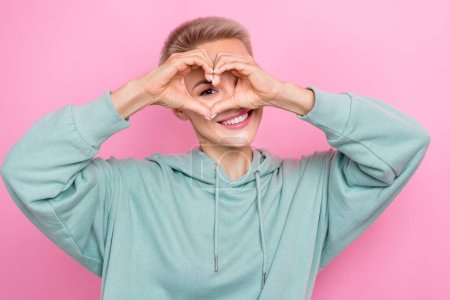 Photo portrait of attractive young woman hide face show heart gesture peek dressed stylish khaki outfit isolated on pink color background.