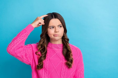 Photo of doubtful unsure lady wear pink sweater finger head looking empty space isolated blue color background.
