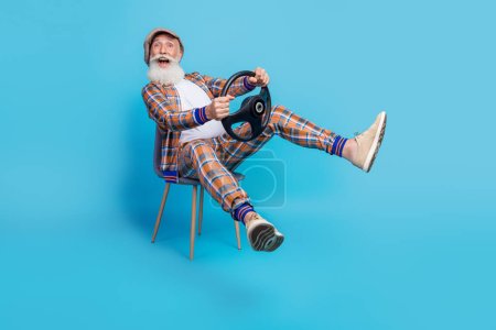 Photo of crazy overjoyed retored man dandy moving new car buy own vehicle rejoice travel trip isolated on blue color background.