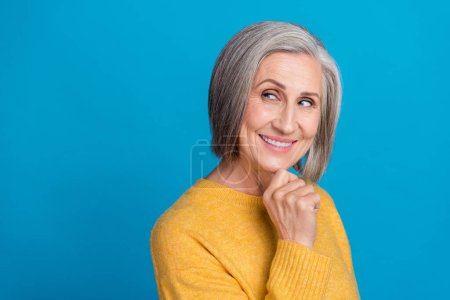 Photo portrait of mature lovely lady intelligent look empty space create plan wear trendy yellow outfit isolated on blue color background.