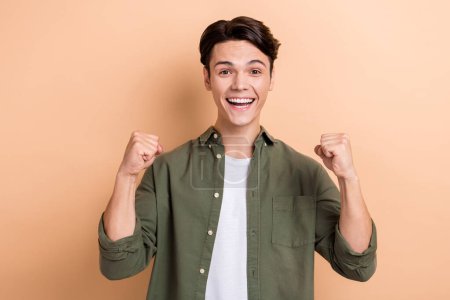 Photo of cheerful delighted person raise fists accomplishment luck isolated on beige color background.