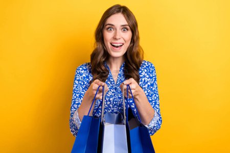 Photo of overjoyed cute lady wear trendy clothes hold packs rejoice buy low prices special offer isolated on yellow color background.
