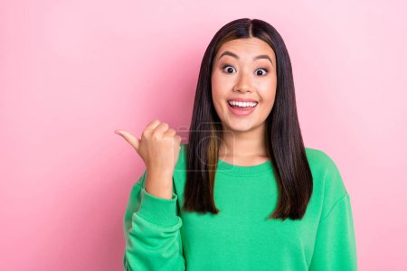 Photo of astonished excited funny positive japanese girl direct finger empty space unbelievable cheap price isolated on pink color background.