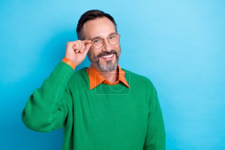 Portrait of positive cheerful man hand touch glasses beaming smile empty space isolated on blue color background.
