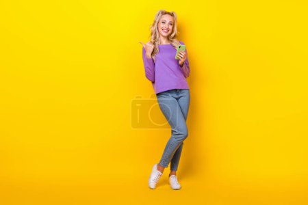 Full length photo of pretty funny lady dressed purple shirt writing modern device thumb emtpy space isolated yellow color background.