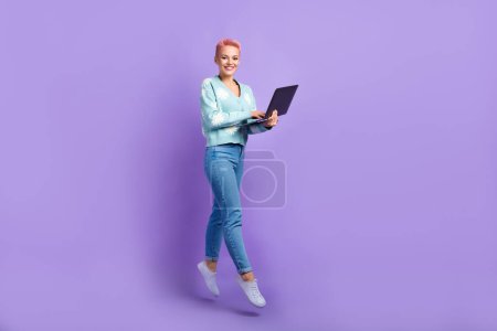 Foto de cuerpo entero de mujer joven positiva usar rosa pelo corto celebrar netbook equipo remoto reunión de negocios aislado sobre fondo de color violeta.