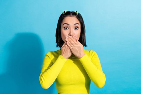 Photo portrait of young funny scared japanese model girl close mouth hands scared look stressed nightmare isolated on blue color background.