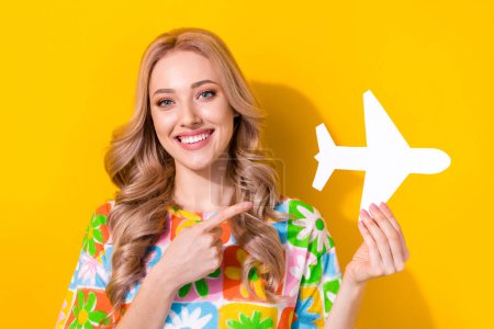 Photo of cute attractive lady direct finger paper airplane choose airline vacation wear floral shirt isolated yellow color background.
