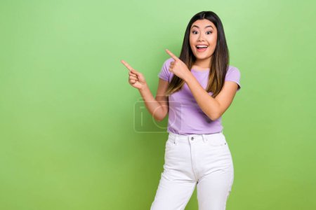 Photo of charming young japanese girl pointing fingers empty space presentation price list restaurant isolated on green color background.