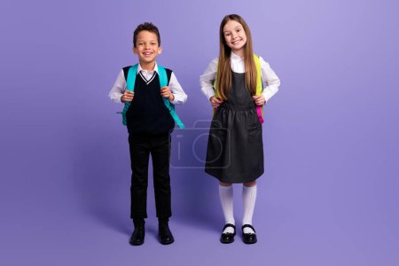 Photo of smart clever kids pupils ready for first september school day buying schoolbags isolated purple color background.
