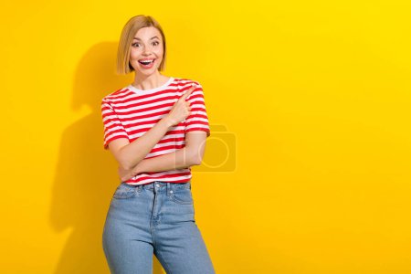 Portrait of impressed funky girl with bob hairstyle wear t-shirt indicating at big sale empty space isolated on bright yellow background.