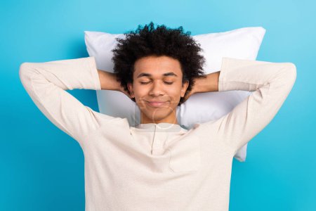 Portrait of nice satisfied young man hands behind head comfort cushion closed eyes isolated on blue color background.