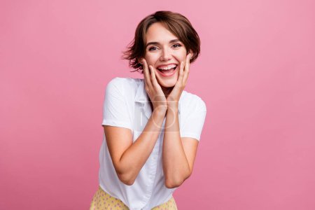 Porträt eines positiven freundlichen Mädchens mit kurzer Frisur tragen stilvolle Bluse halten Handflächen auf Wangenknochen isoliert auf rosa Hintergrund.