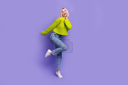 Full length photo of excited funky lady wear green pullover arm cheek looking empty space isolated purple color background.