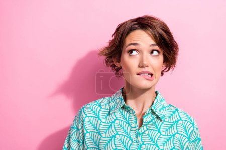 Photo of minded pretty lady biting lips look empty space decide ponder isolated on pink color background.