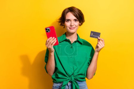 Foto von fröhlichen positiven Mädchen gekleidet grünes Hemd Online-Shopping modernes Gadget isoliert gelben Farbhintergrund.