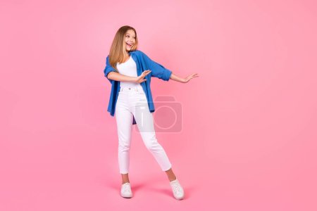 Foto de cuerpo entero de chica bastante despreocupada usar camisa azul disfrutando discoteca espacio vacío aislado color rosa fondo.