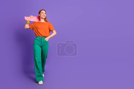 Photo of cheerful optimistic girl wearing trendy clothes walking street looking empty space poster isolated on purple color background.