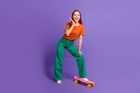 Full length photo of glad optimistic girl standing skate spending weekend riding pennyboard isolated on violet color background.