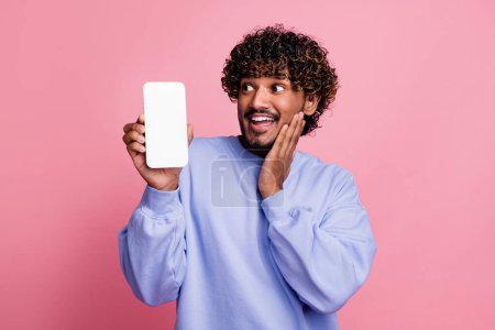Foto-Porträt von attraktiven jungen Mann sehen verträumt erstaunt weißen Bildschirm Gerät tragen trendige blaue Kleidung isoliert auf rosa Hintergrund.