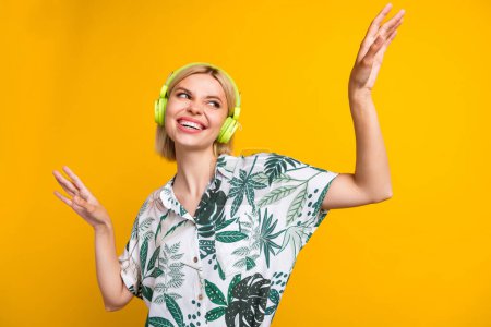 Photo of dreamy cheerful lady wear print shirt headphones having fun dancing isolated yellow color background.