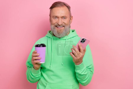 Photo of positive good mood guy dressed green hoodie enjoying coffee chatting instagram twitter telegram facebook isolated pink color background.