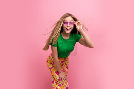 Foto retrato de encantadora dama adolescente tienen toque divertido gafas de sol excitado posando desgaste ropa verde de moda aislado sobre fondo de color rosa.