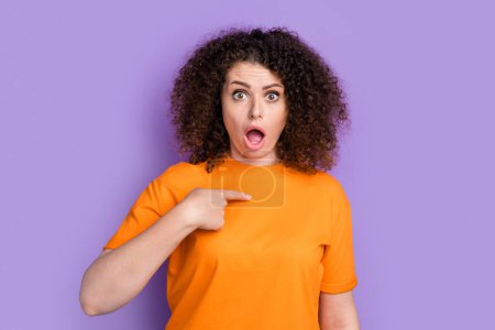 Foto de sorprendida dama impresionada vestida naranja camiseta señalando dedo ella misma boca abierta aislado color violeta fondo.