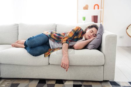 Foto von müde überarbeitete Kerl kariertes Hemd gekleidet liegendes Sofa mit Tagtraumschlaf im Haus zu Hause Zimmer.