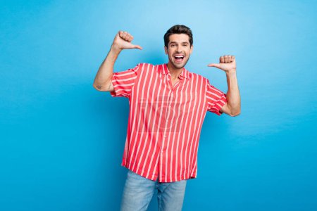 Photo of optimistic confident perky man with bristle dressed striped shirt indicating at himself isolated on blue color background.
