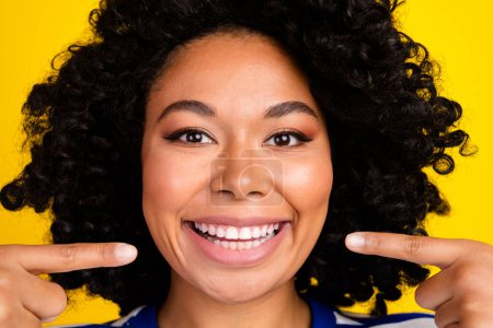 Close up portrait of cheerful lovely cute girl showing healthy white teeth veneers advertise toothpaste isolated on yellow color background.