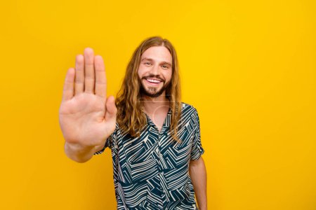 Photo of attractive funky guy wear print shirt showing arm palm high five isolated yellow color background.