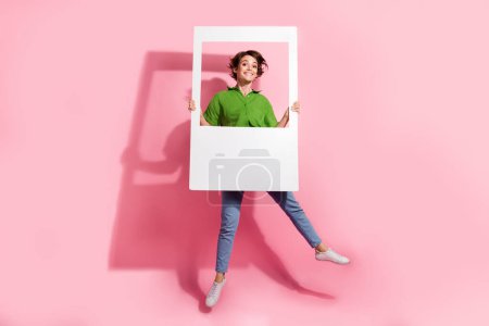 Full-Size-Porträt von unbeschwerten verrückten Mädchen springen Hände halten Papier Album Set Karte isoliert auf rosa Hintergrund.