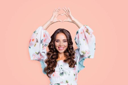 Portrait of good-looking, magnificent, exquisite brunette showing love symbol, heart shape with fingers above head looking at camera isolated on bright teal background.